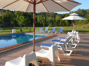 um grupo de cadeiras e guarda-sóis ao lado de uma piscina em Monte Do Adail Turismo Rural Casa De Campo em Vila Nova de Milfontes