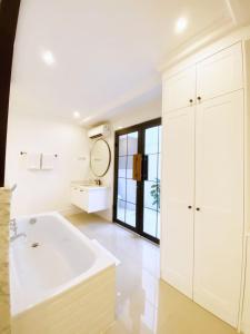 een witte badkamer met een bad en een wastafel bij Loewys Home Tanjung Duren Jakarta Barat in Jakarta
