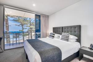 - une chambre avec un grand lit et un balcon dans l'établissement Headlands Austinmer Beach, à Austinmer