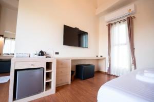 a bedroom with a tv on a wall and a bed at De MALA in Sukhothai