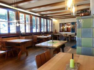 a restaurant with wooden tables and chairs and windows at Sporthostel Rössle in Schluchsee