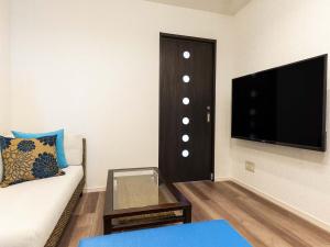 a living room with a couch and a flat screen tv at Yukurina Resort Okinawa in Motobu