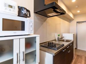 a kitchen with a microwave and a sink at Yukurina Resort Okinawa in Motobu