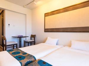 two beds in a room with a table and chairs at Yukurina Resort Okinawa in Motobu