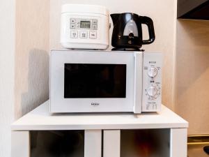 a microwave with a coffee maker on top of it at Yukurina Resort Okinawa in Motobu