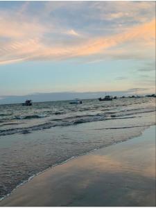 een strand met boten in het water bij zonsondergang bij Suítes Mar de Maragogi in Maragogi
