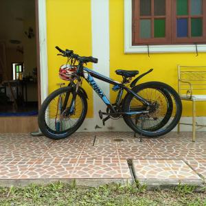 uma bicicleta estacionada em frente a uma casa amarela em Baan Bussaba Hotel em Trang