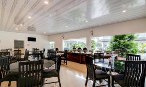 - une salle à manger avec des tables, des chaises et des fenêtres dans l'établissement Treebo Trend Misty Garden Resorts With Mountain View, à Munnar