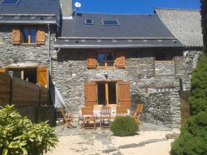 a stone house with a table and chairs in front of it at Les Granges de la Fontaine in Antignac