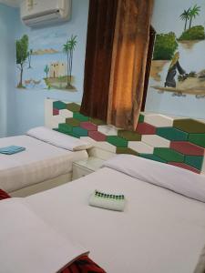 um quarto com duas camas e um quadro na parede em Awi Guest House em Aswan