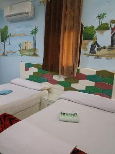 Zimmer mit 2 Betten und Wandgemälde in der Unterkunft Awi Guest House in Assuan