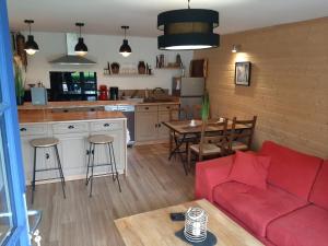 a living room with a red couch and a kitchen at Le logis du héron in Coulon