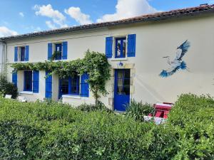 a white house with blue shutters and a bird at Le logis du héron in Coulon