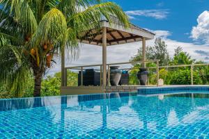 uma piscina com um gazebo ao lado de uma palmeira em Tranquility villa em Baie Sainte Anne