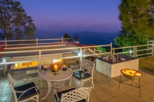 a patio with a table and chairs on a balcony at StayVista at The Haven 3BR Villa in Kasauli with Scenic Panoramic Views in Kasauli