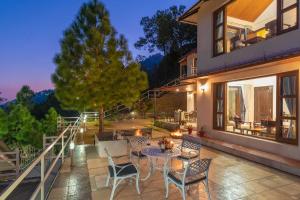 a patio with a table and chairs on a building at StayVista at The Haven 3BR Villa in Kasauli with Scenic Panoramic Views in Kasauli