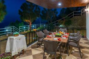 a patio with a table and chairs on a balcony at StayVista at The Haven in Kasauli