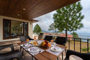 a table on a patio with a view of the ocean at StayVista at The Haven 3BR Villa in Kasauli with Scenic Panoramic Views in Kasauli +43 photos