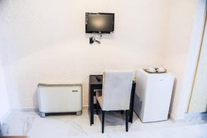 a table with a chair and a television on a wall at Valentino Hotel in Kremasti