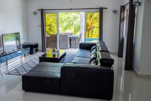a living room with a black couch and a television at Tranquility villa in Baie Sainte Anne