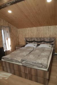 a bed in a room with a wooden wall at Fish Hotel in Akhalk'alak'i