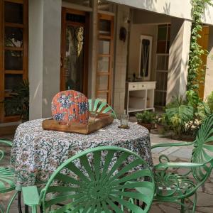 a table with green chairs and a plate on it at Mukam, Boutique Homestay in Jaipur