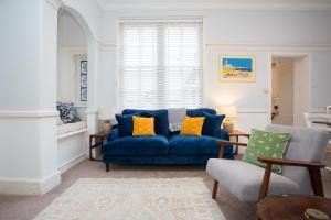 a living room with a blue couch and two chairs at The Old Coastguard House in Worthing