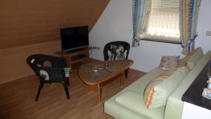 uma sala de estar com um sofá, uma mesa e uma televisão em Ferienwohnung Irene em Ludwigschorgast