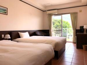 um quarto de hotel com duas camas e uma janela em Pine Shima Resort Coral Fish em Ibaruma