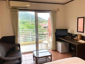 Habitación de hotel con cama, escritorio y ventana en Pine Shima Resort Coral Fish en Ibaruma