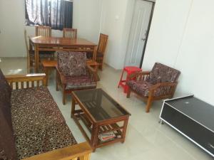 a living room with wooden chairs and tables at Snehabandh in Dapoli
