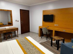 a hotel room with a bed and a desk and a television at Traveller Inn Hotel Appartments in Al Khobar