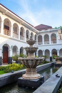 einen Brunnen vor einem großen Gebäude in der Unterkunft Daroessalam Syariah Heritage Hotel in Pasuruan