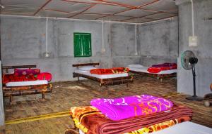 a room with four beds and a fan at Okegiga Homes in Majuli