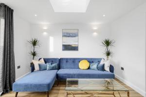 un salon avec un canapé bleu et une table en verre dans l'établissement Modern Bungalow in Maidstone sleeps 5 with free parking, à Maidstone
