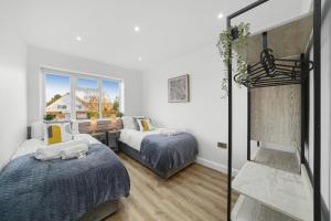 a bedroom with two beds and a desk and a window at Modern Bungalow in Maidstone sleeps 5 with free parking in Maidstone