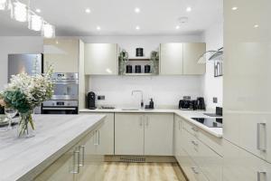 a kitchen with white cabinets and a vase of flowers at Modern Bungalow in Maidstone sleeps 5 with free parking in Maidstone