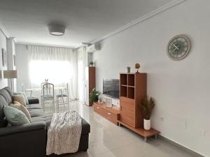 ein Wohnzimmer mit einem Sofa und einer Uhr an der Wand in der Unterkunft Bellas Artes in Murcia