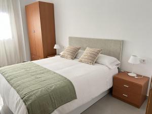 una camera da letto con un grande letto bianco con due cuscini di Bellas Artes a Murcia