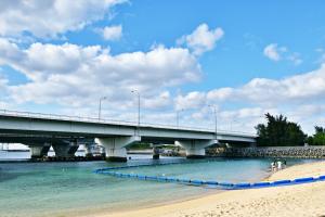 a bridge over the water with a sandy beach at TOMMY CONDOMINIUM WAKASA 401 in Naha