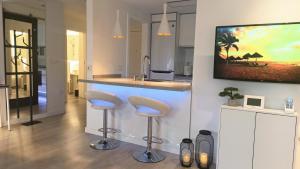 a kitchen with a bar with stools and a tv on the wall at Casa Fuerte Playa in La Herradura