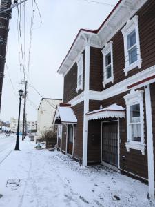 una casa marrone con la neve sul lato di 元町の宿　雪月花 a Hakodate