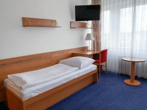 Bett in einem Zimmer mit einem Schreibtisch und einem TV. in der Unterkunft Hotel ILF in Prag