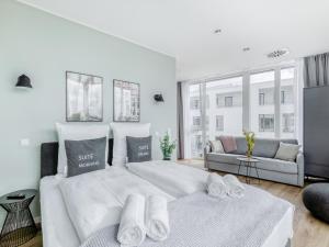 a white bedroom with a large bed and a couch at limehome Mönchengladbach Fliethstraße in Mönchengladbach