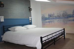 a bed with white sheets and pillows in a room at Logement de La Sittelle in Aizenay