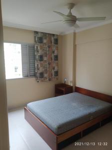 ein Schlafzimmer mit einem Bett und einem Deckenventilator in der Unterkunft Apto a 25 metros areia PITANGUEIRAS Vista mar 4 quartos 3 banheiros 1 vaga carro Serviço de praia in Guarujá