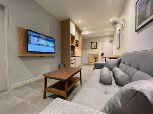 LV Modern Suite Langkawi by Zervin في كواه: غرفة معيشة مع أريكة وتلفزيون على الحائط