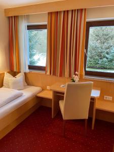 ein Hotelzimmer mit einem Bett, einem Schreibtisch und einem Fenster in der Unterkunft W3 Haus Ganghofer in Leutasch