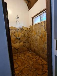 a stone shower in a bathroom with a stone wall at Honey Badger Lodge in Moshi