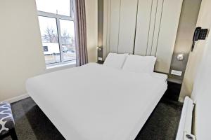 białe łóżko w pokoju z oknem w obiekcie OYO The Baltimore Hotel w mieście Middlesbrough